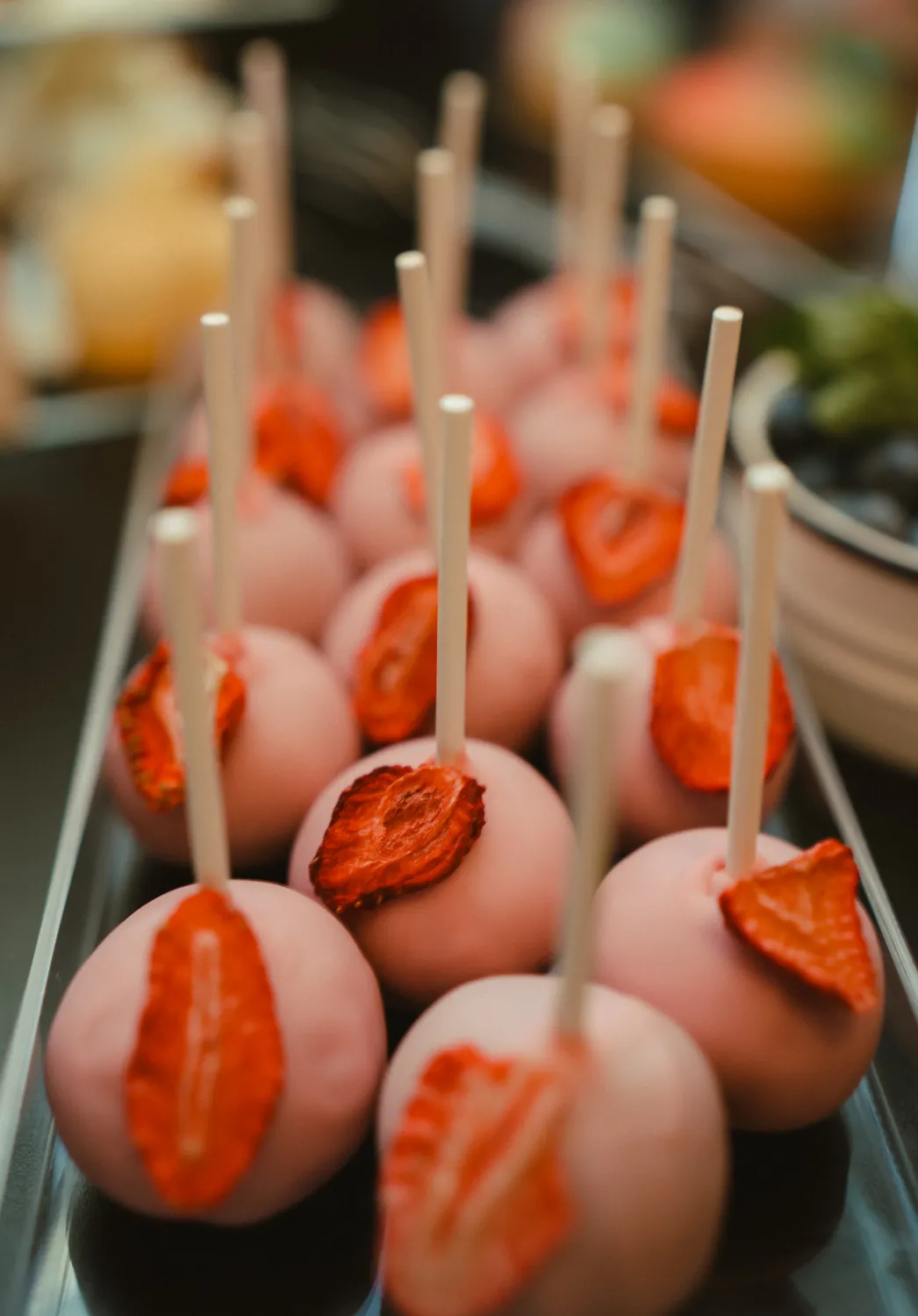 Rosa glasierte Cake-Pops dekoriert mit Erdbeerscheiben am Stiel