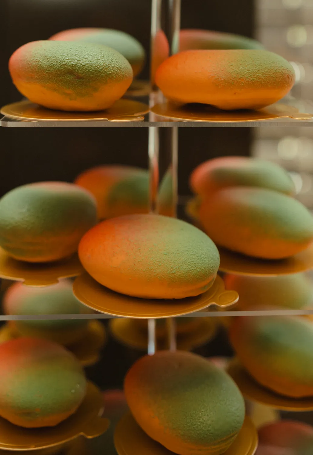 Törtchen in täuschend echter Mango-Form mit Farbverlauf auf einer Etagere