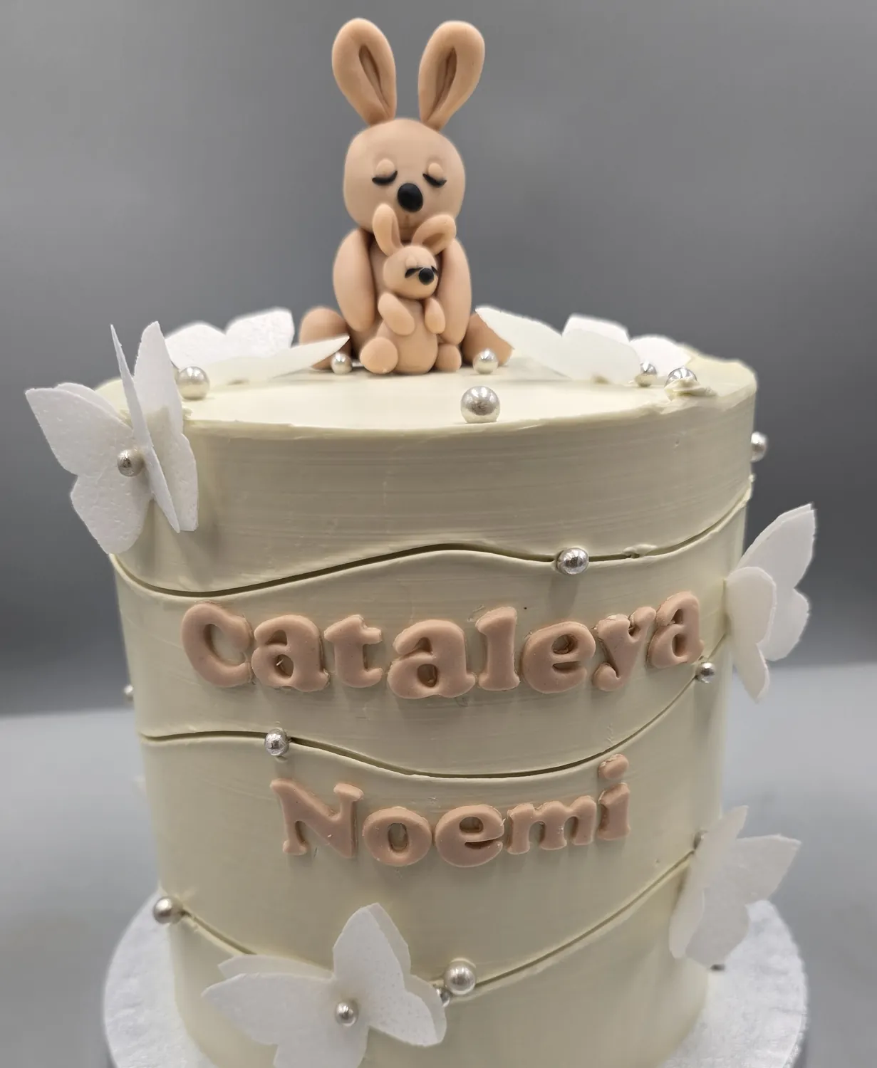 Geburtstagstorte mit Namen, Schmetterlingen und einer kleinen Tierfigur aus Fondant