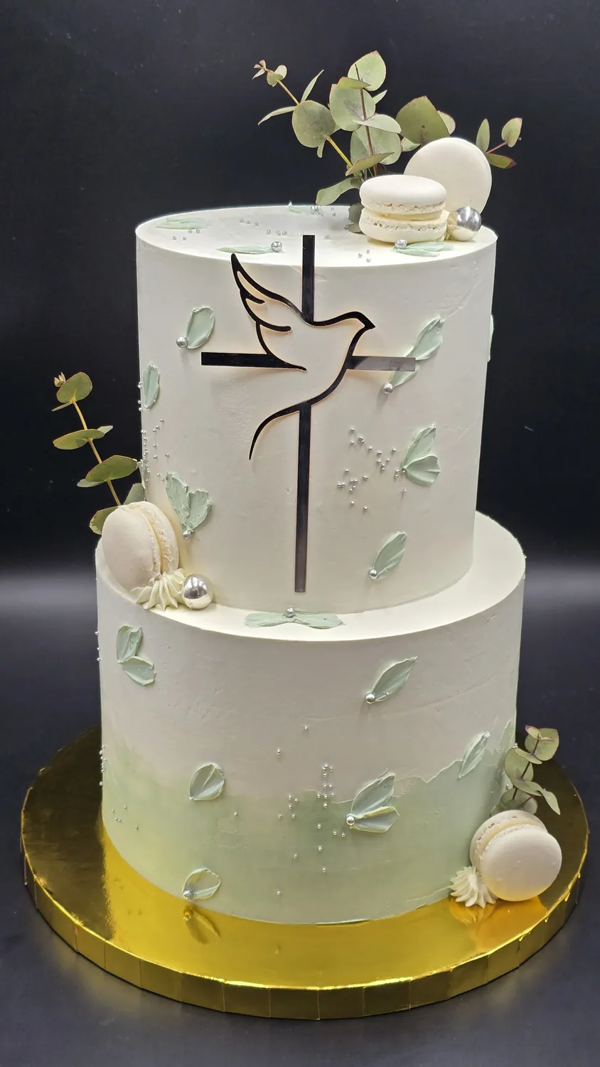 Zweistöckige weiße Tauftorte mit Kreuz, Taube und zarten grünen Blättern
